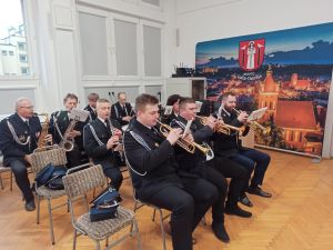 Orkiestra strażacka odgrywająca utwór na instrumentach.