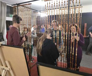 grupa osób oglądająca koraliki i słuchająca przez słuchawki historii dotyczącej wspomień o kobietach