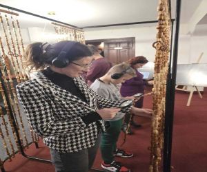 Pani Burmistrz oglądająca korale przez lupę i słuchająca na słuchawkach wspomień o kobietach