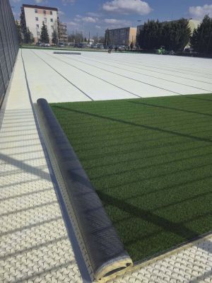 rozkładanie sztucznej murawy na boisku